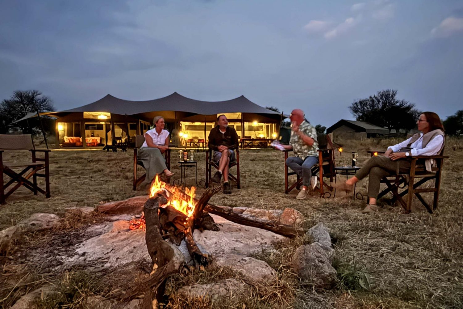 Parents and children sitting around a campfire at a safari lodge