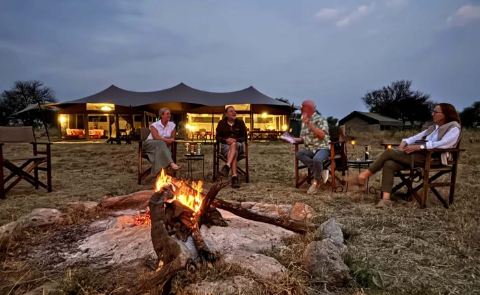 Parents and children sitting around a campfire at a safari lodge