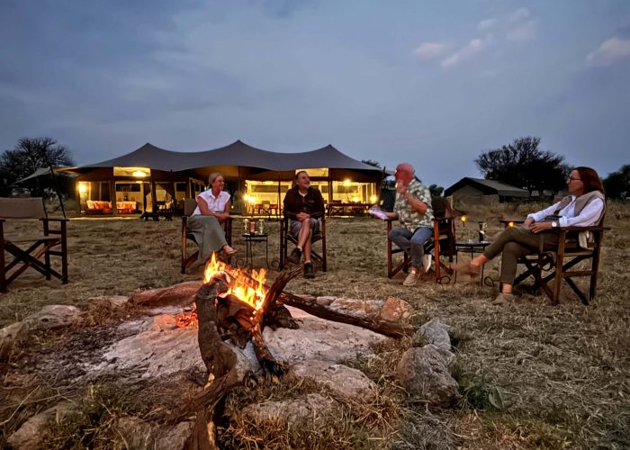 Parents and children sitting around a campfire at a safari lodge